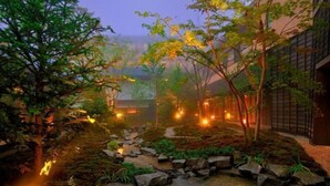 Un giardino tranquillo con un vialetto in pietra, alberi e un edificio dall'architettura tradizionale.