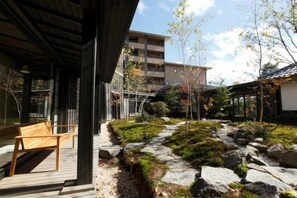 A wooden bench, a stone pathway, and a building with a traditional roof.