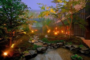 A landscaped garden with a water feature, stone pathway, and trees. - Konoha (Kusatsu)