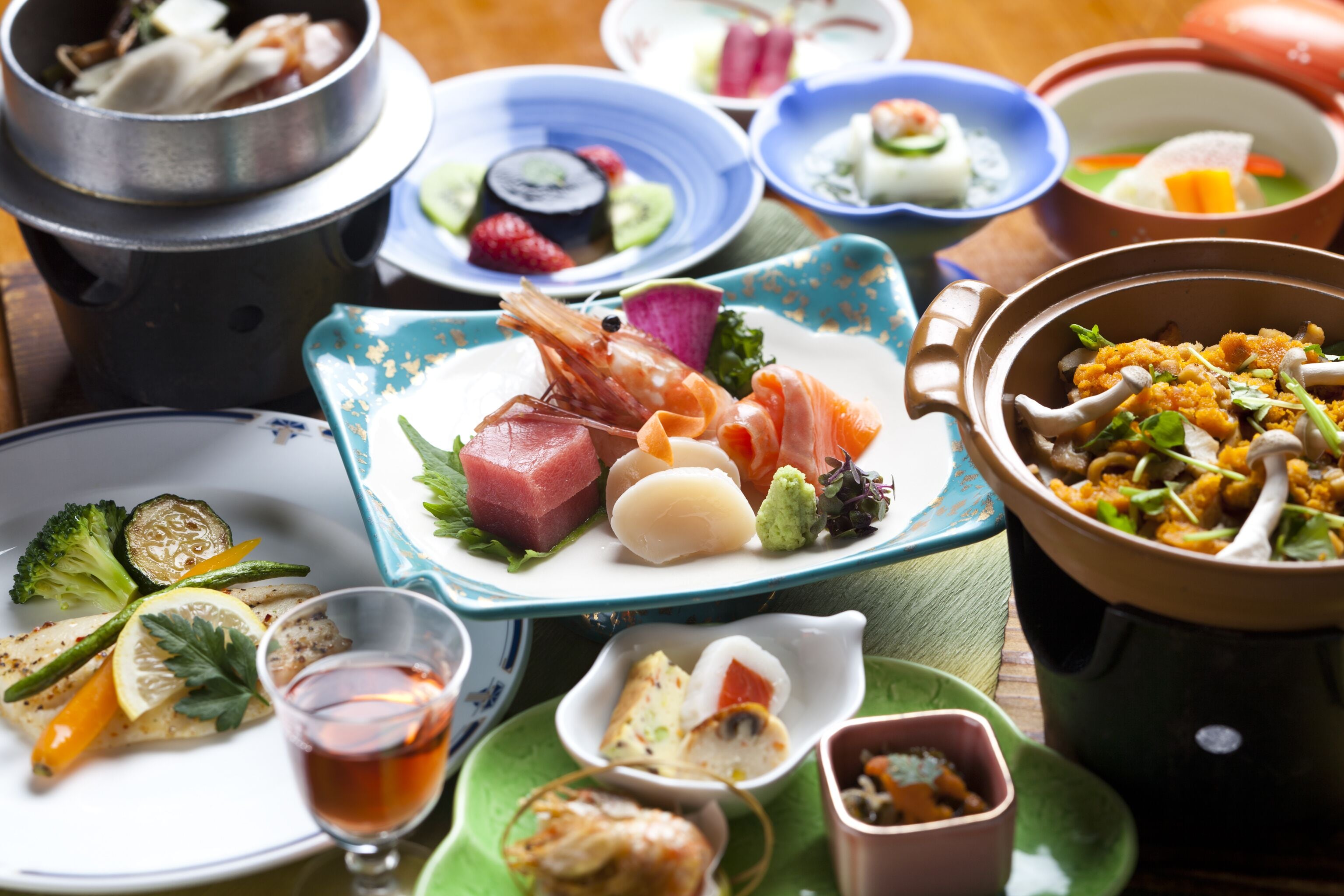 A variety of dishes on a table, including sushi, sashimi, and other Asian cuisine.