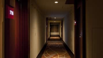 Pasillo de hotel con suelo alfombrado, un cartel con el número '715' a la izquierda y puertas a ambos lados.