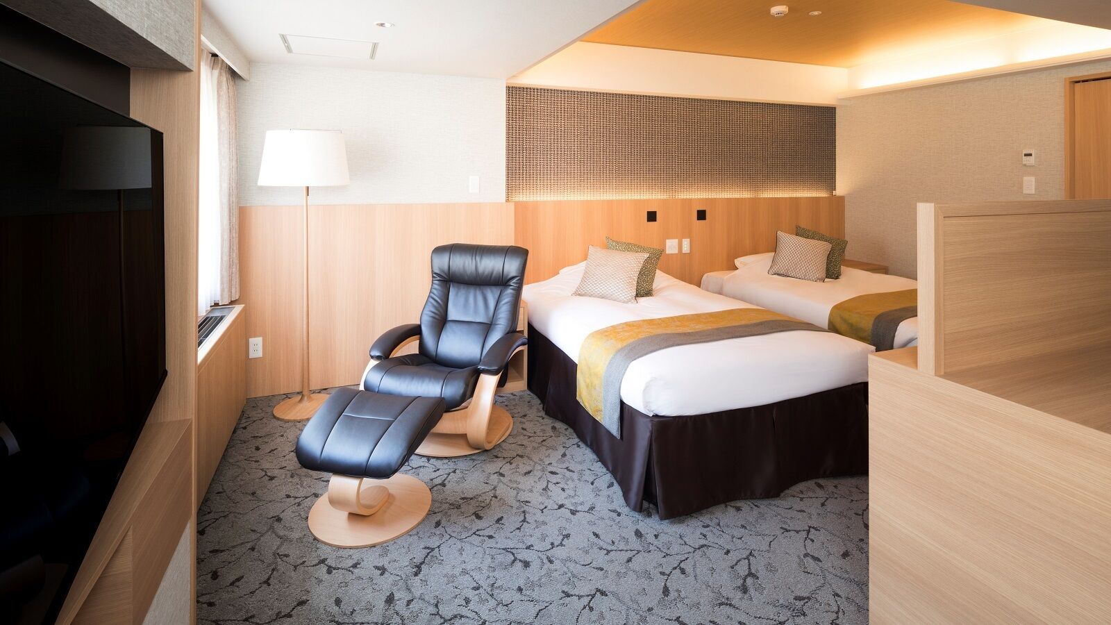 Ein Hotelzimmer mit Bett, Massagesessel, Schreibtisch und Fernseher.