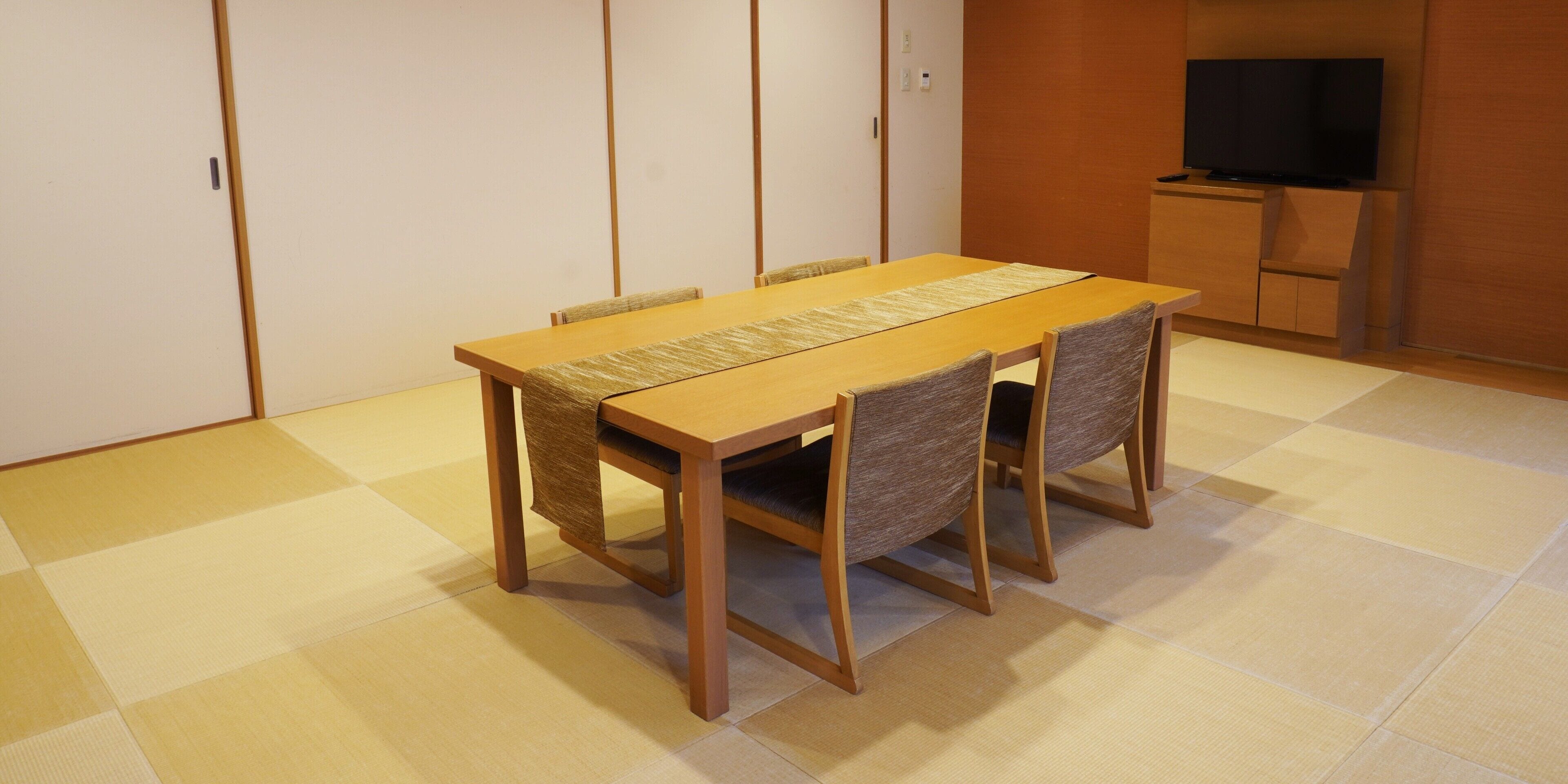 Et traditionelt japansk værelse med tatami-gulvbelægning, et lavt træbord og fire stole.