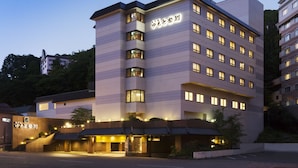 Un hôtel à plusieurs étages, doté d’un design moderne, avec une entrée imposante et de nombreuses fenêtres à chaque étage.