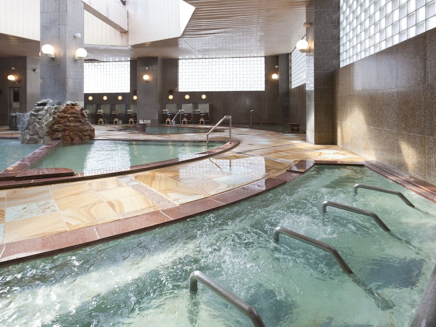An indoor swimming pool with multiple lanes, a rock formation, and seating areas.