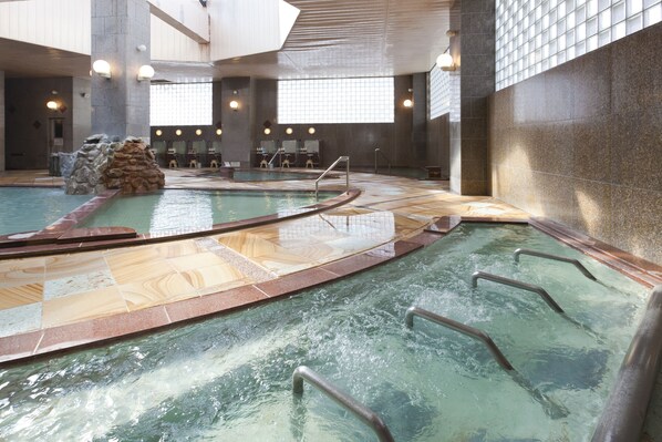 An indoor swimming pool with multiple lanes, a rock formation, and seating areas. - Hotel Yumoto Noboribetsu (Noboribetsu)