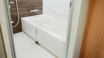 A modern bathroom with a white bathtub, a shower area, and a glass shower door.