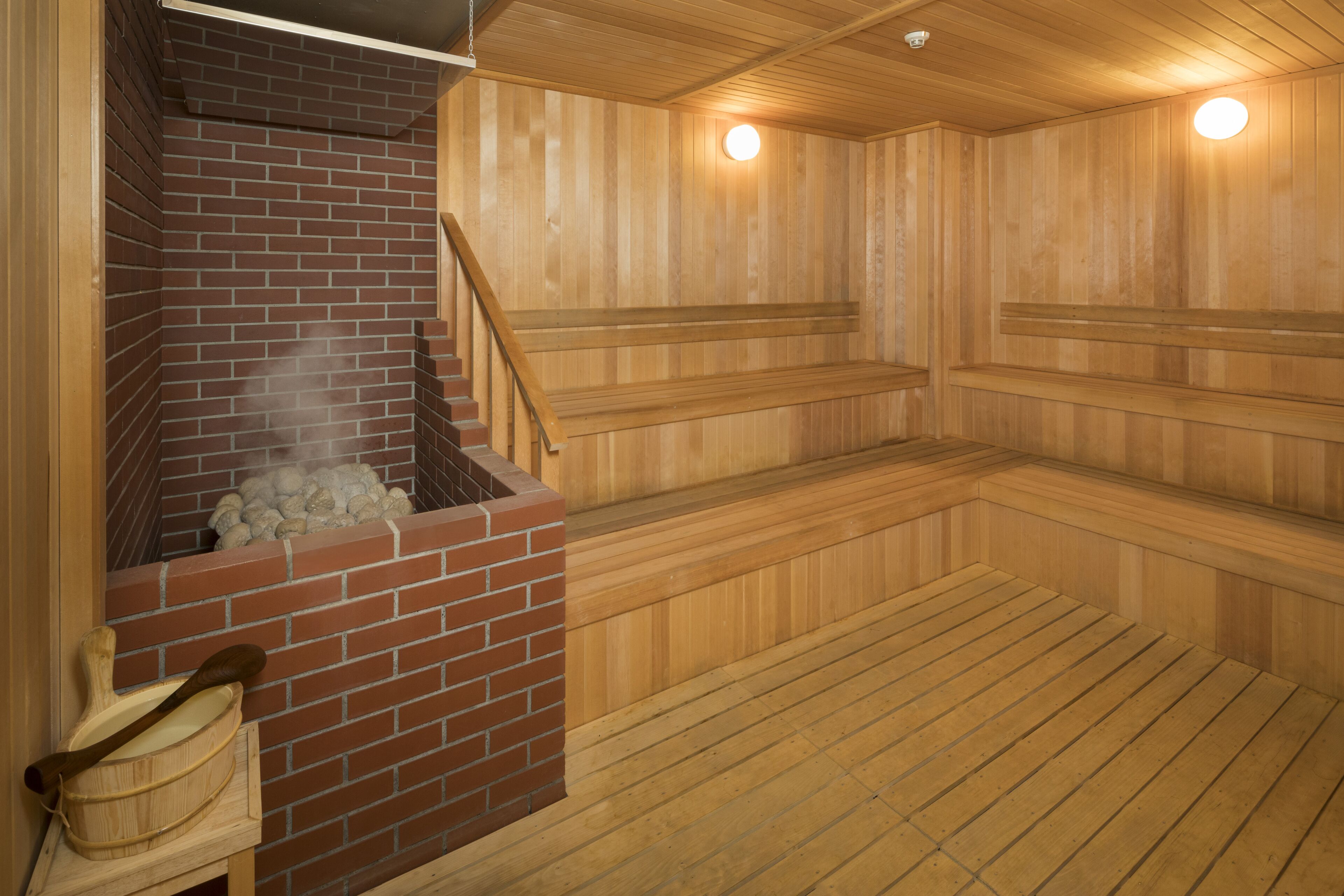 A sauna with wooden benches, a brick sauna room, and a wooden floor.