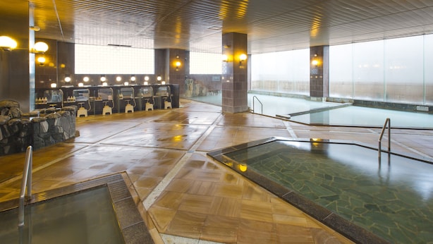 Un vaste espace intérieur abritant une piscine, agrémenté de plusieurs coins salon et d’une grande fenêtre laissant entrer la lumière naturelle.