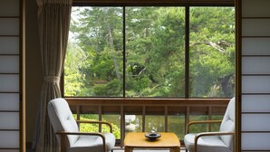 A room with a large window, two chairs, and a small table. - Ikuji Onsen TANAKAYA (Kurobe)