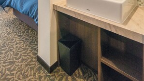 Un baño de hotel con un espejo grande, un lavabo blanco y un salpicadero de azulejos.