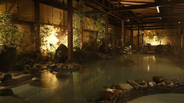 Un onsen japonés tradicional con un baño de piedra rodeado de rocas y paredes de bambú.