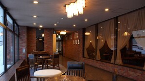 Ein Restaurant mit Backsteinwänden, großen Fenstern und einer Mischung aus Holz- und Polstermöbeln.