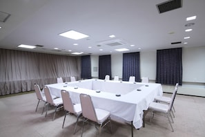 A conference room with a rectangular table, white chairs, and a white tablecloth. - Wakkanai Sun Hotel (Wakkanai)