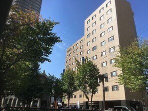 Un edificio de varios pisos con fachada plana, numerosas ventanas y cielo despejado.