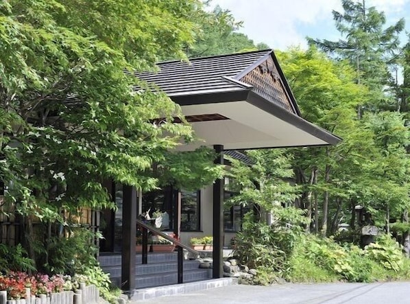 Un bâtiment moderne doté d’un toit en pente, entouré d’une végétation luxuriante.