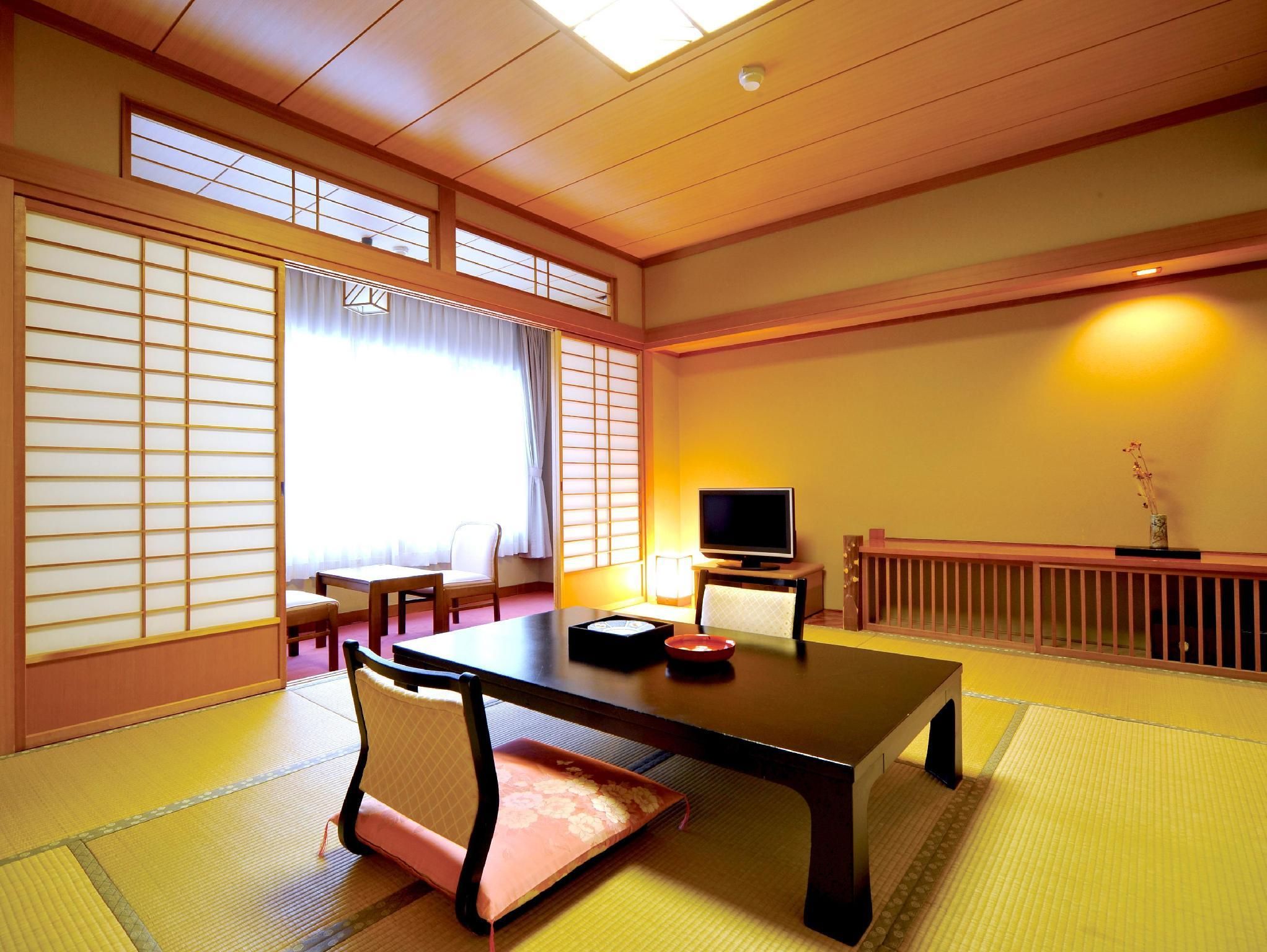 A traditional Japanese room with tatami flooring, a low table, a television, and sliding doors.