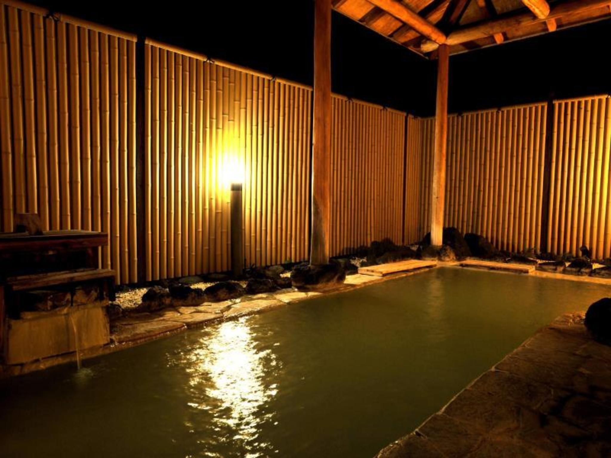 A swimming pool with bamboo walls and a wooden deck.