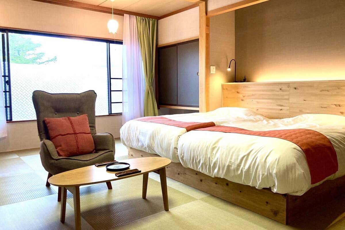 A bedroom with a bed, a chair, a table, and a TV.