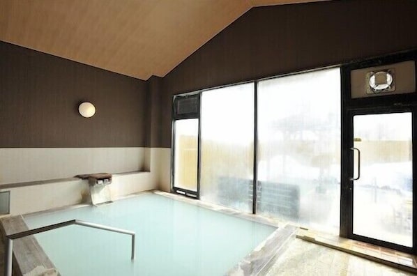 A modern indoor pool with a glass wall, a small seating area, and a ceiling light fixture. - Okunikko Yumoto Onsen Yumoto Itaya (Nikko)