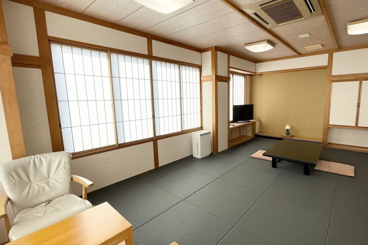 A room with tatami flooring, a television, a small table, and a chair.