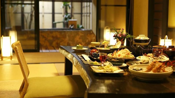 Una mesa de comedor con varios platos, una silla y un florero con flores.
