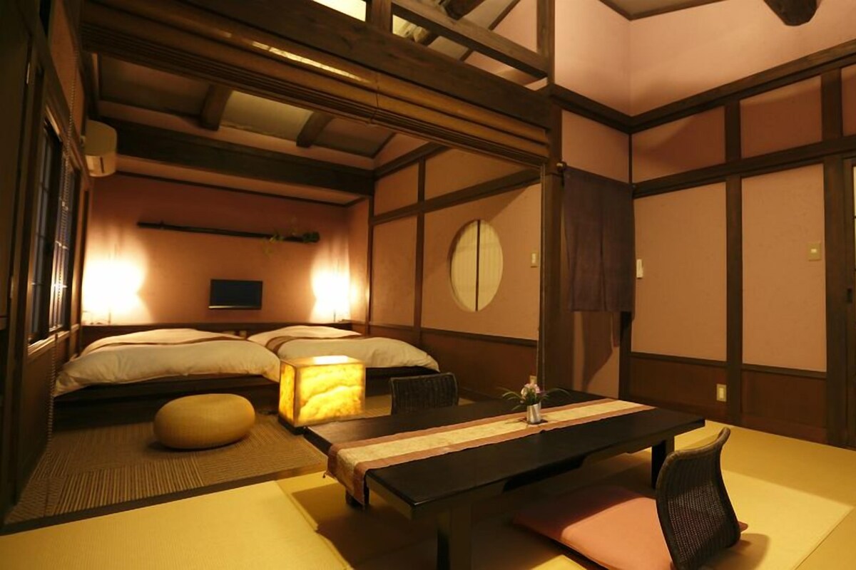 Een traditionele Japanse kamer met tatami vloerbedekking, een lage tafel met kussens en een bed met een kussen.