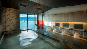 Un spa moderno con una amplia piscina interior, paneles de madera y vistas al mar.