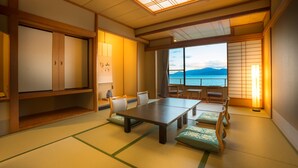 Una habitación japonesa tradicional con suelo de tatami, una mesa baja y vista al mar.
