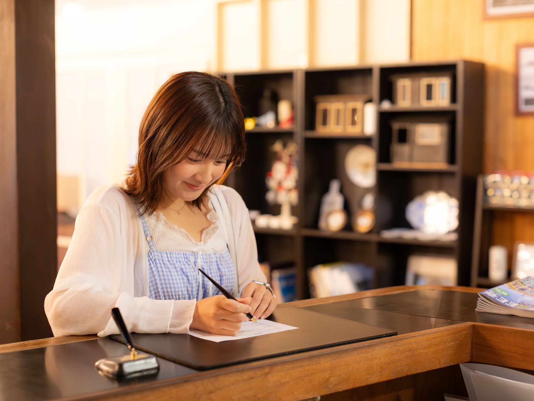 A person sitting at a wooden counter, writing on a piece of paper.
