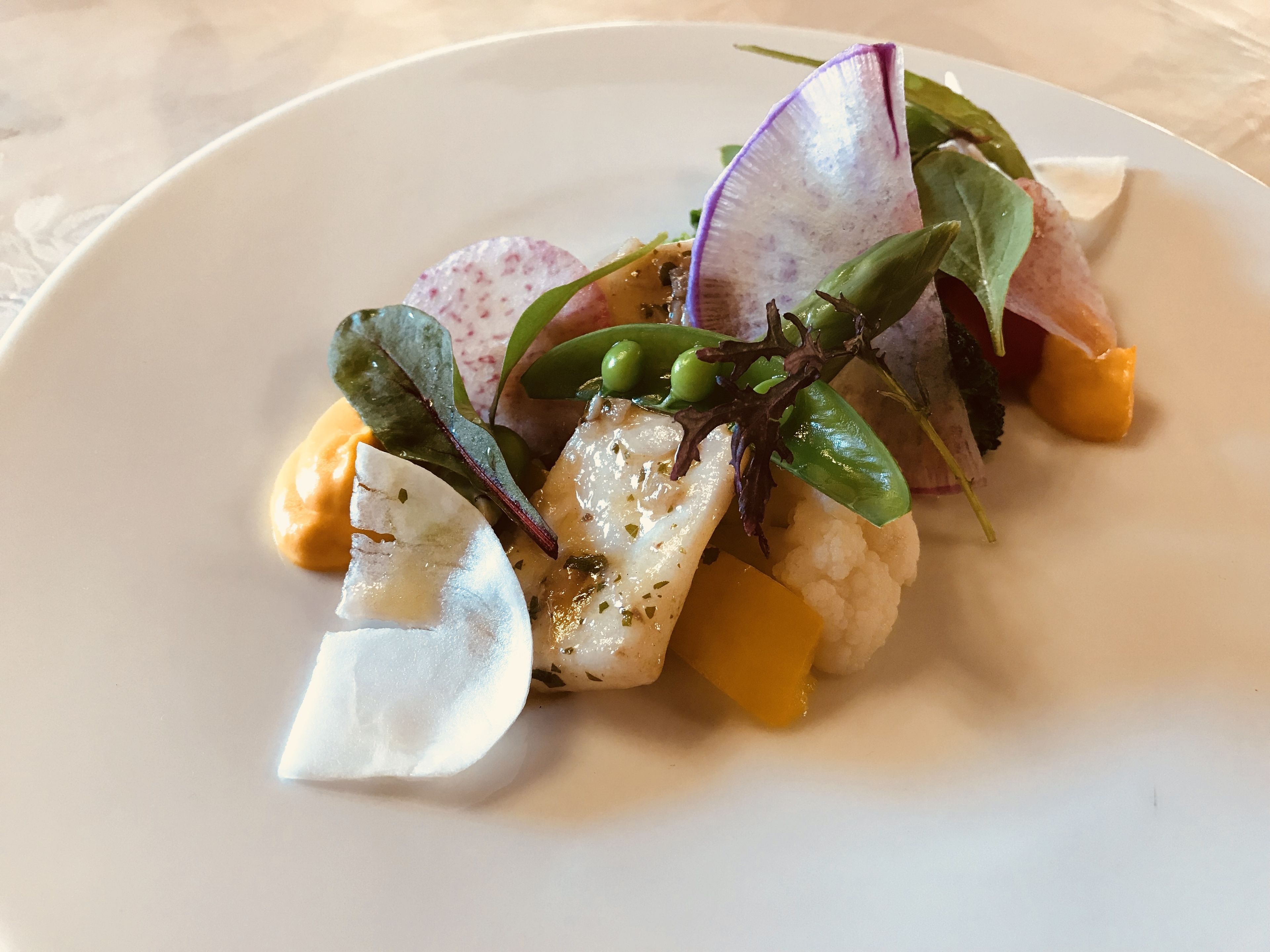 Une assiette contenant divers aliments, notamment du poisson, du chou-fleur et des légumes verts.