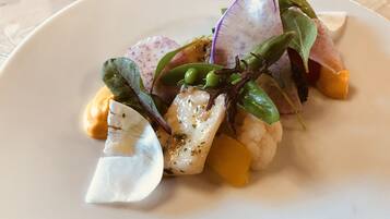 Une assiette contenant divers aliments, notamment du poisson, du chou-fleur et des légumes verts.