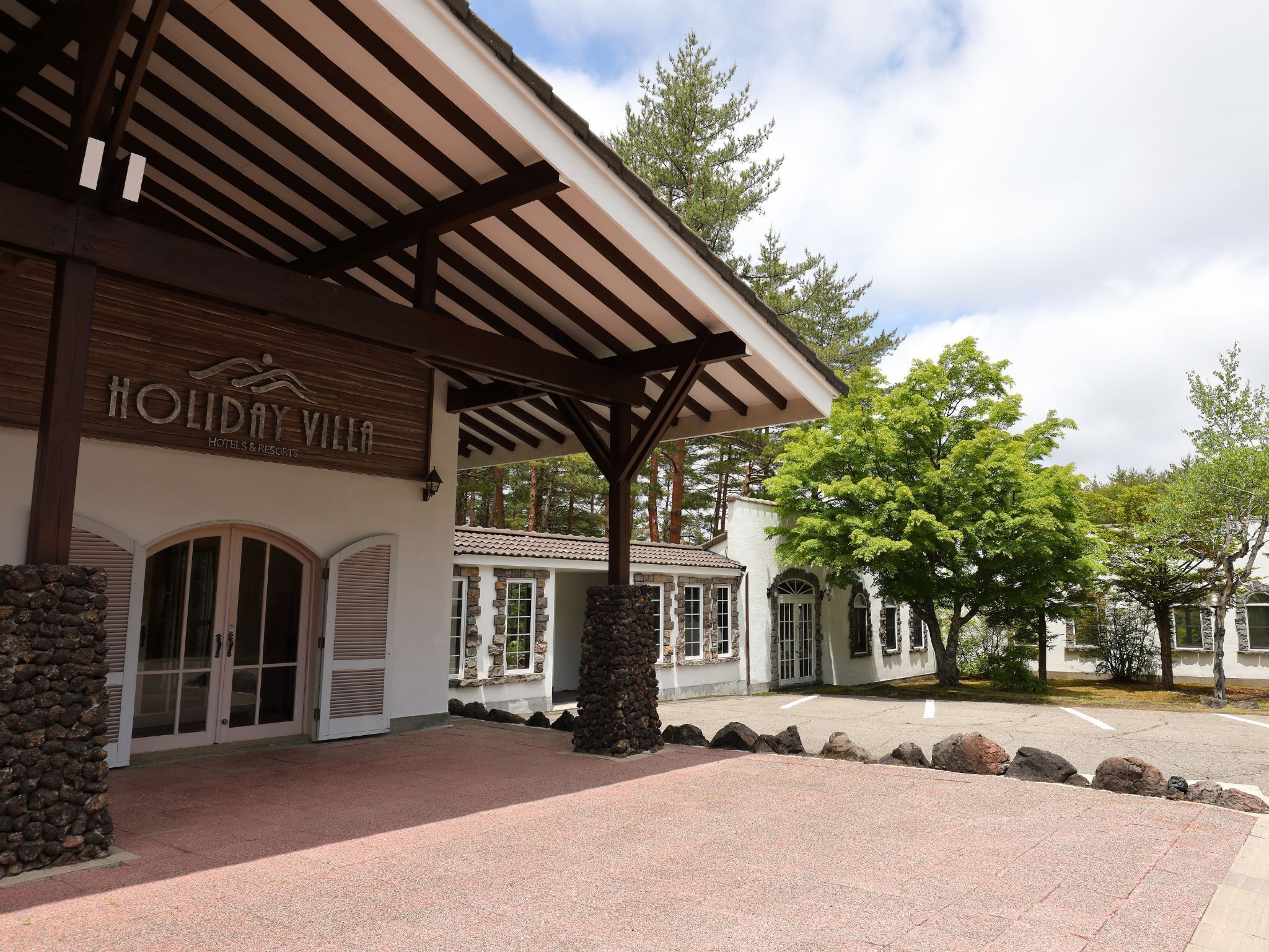 A building with a covered entrance, stone pillars, and a sign reading 'Holiday Villa Hotels & Resorts.'