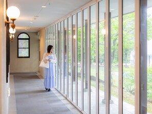 Un couloir doté de grandes fenêtres, d’une porte et d’un luminaire.