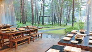 A rustic wooden dining area with benches and tables, surrounded by a forested landscape. - Holiday Villa Hotel & Resort Karuizawa (Tsumagoi)
