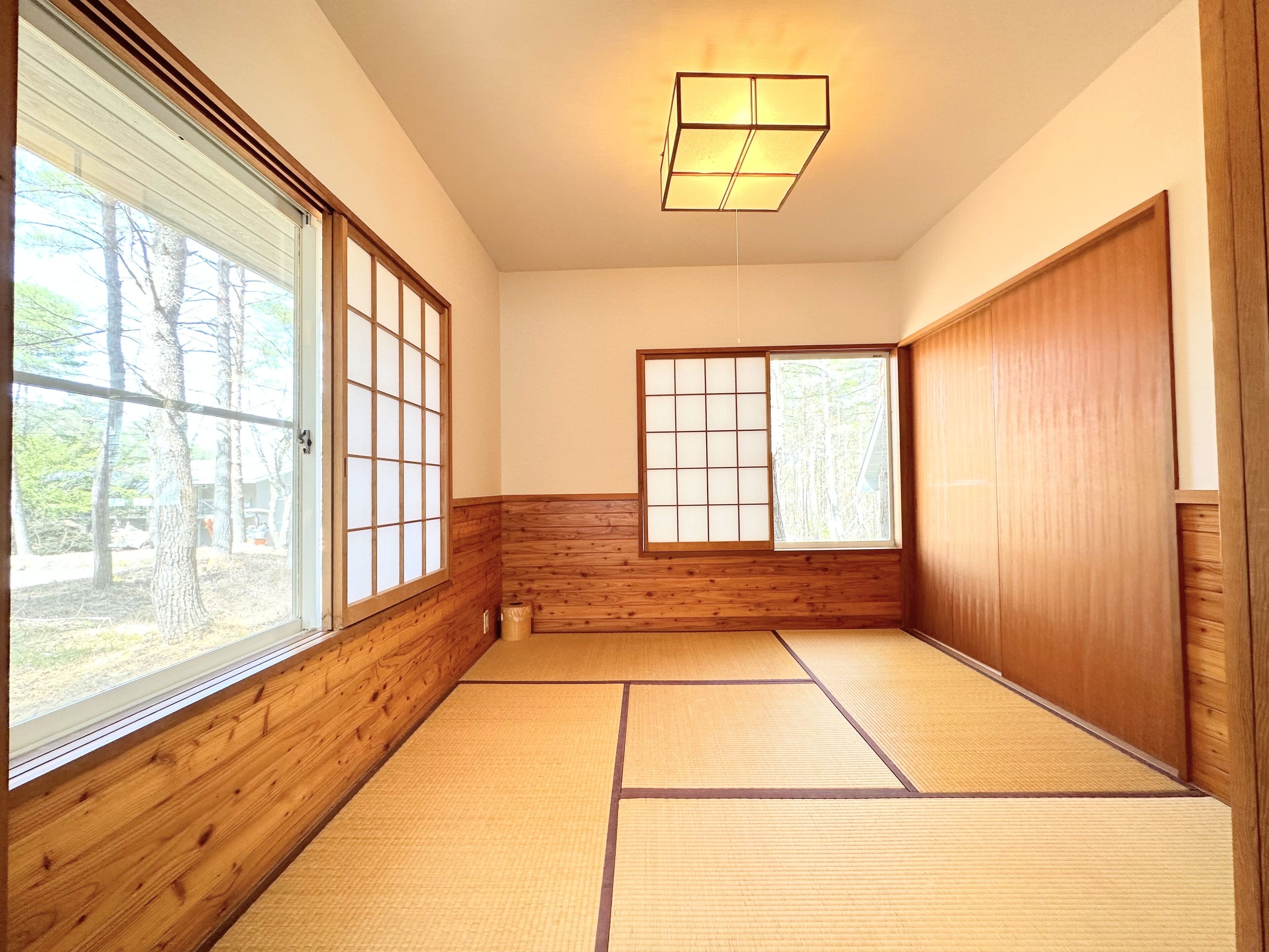 Une pièce de style japonais traditionnel, avec un sol recouvert de tatamis, des portes coulissantes et un luminaire au plafond.