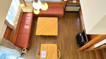 A room with a wooden floor, a red sofa, a wooden table, and a ceiling fan.
