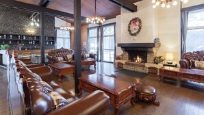 A spacious lounge with leather sofas, a fireplace, and a stone wall. - Holiday Villa Hotel & Resort Karuizawa (Tsumagoi)