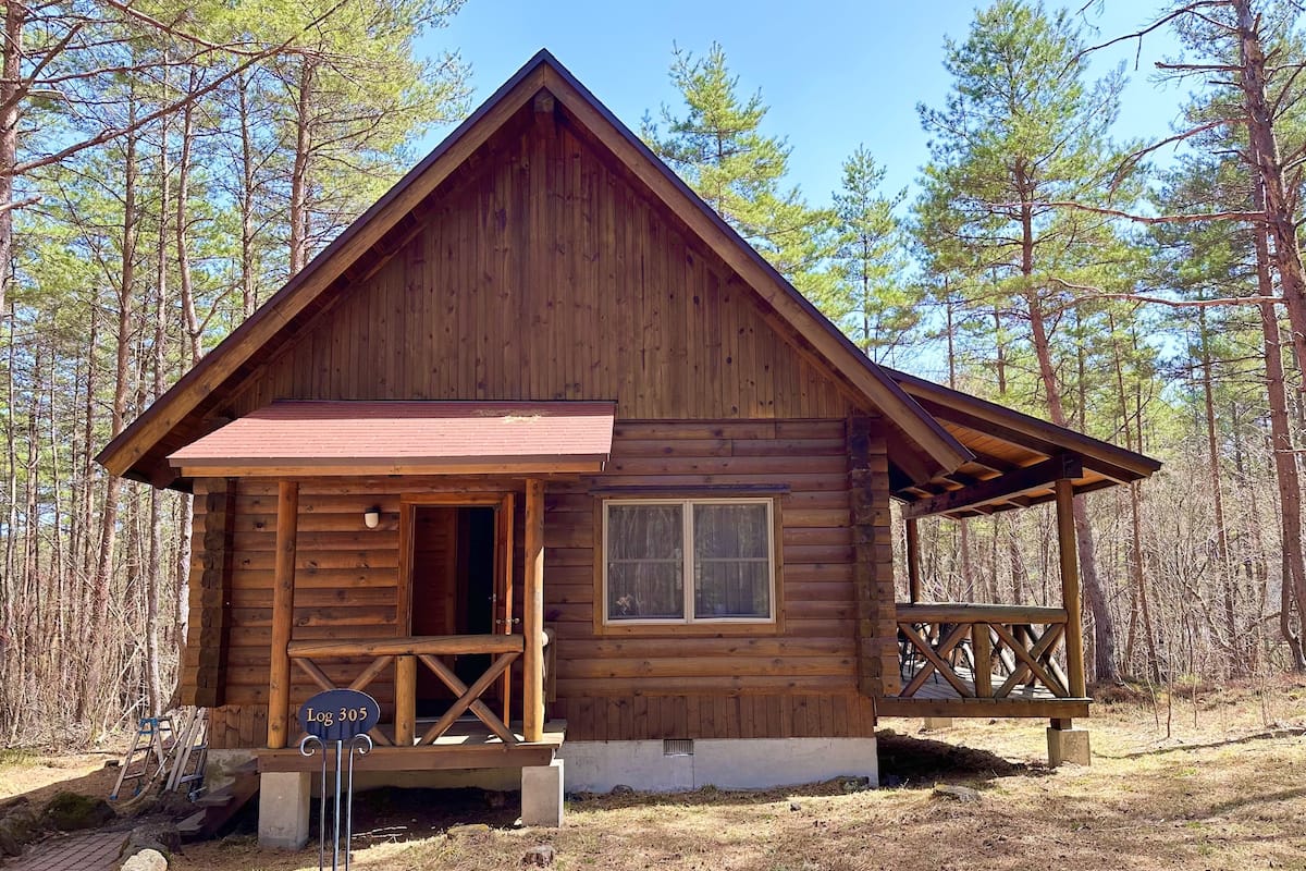 Una cabaña de madera con un porche, una ventana y un letrero que dice "Log 305".