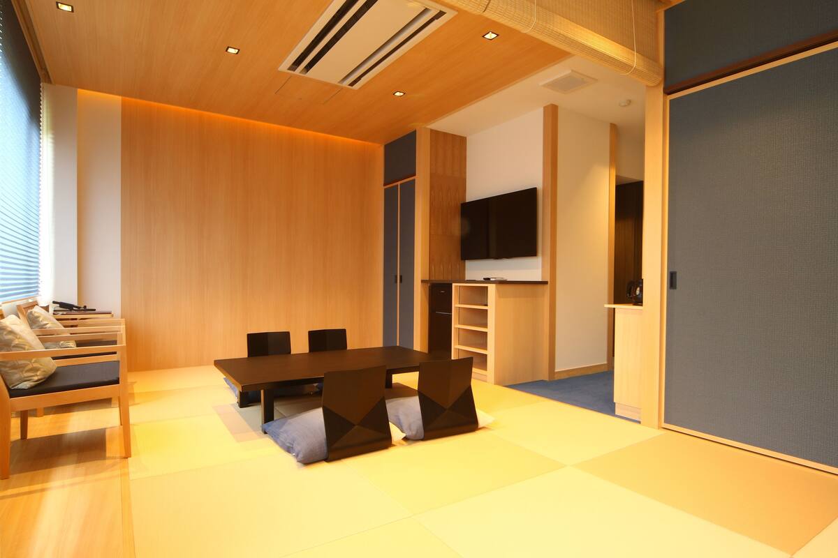 A modern meeting room with a wooden table, chairs, and a flat-screen TV.