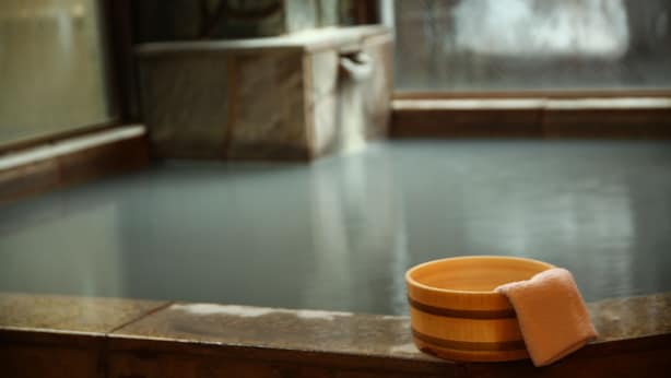 Un cuenco de madera y una toalla sobre un repisa de piedra en un spa.