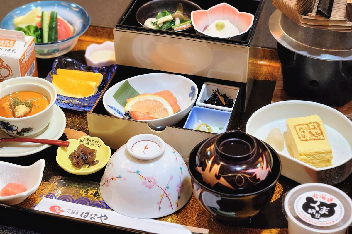 A variety of Japanese dishes including sushi, soup, and pickled vegetables, arranged on a table.