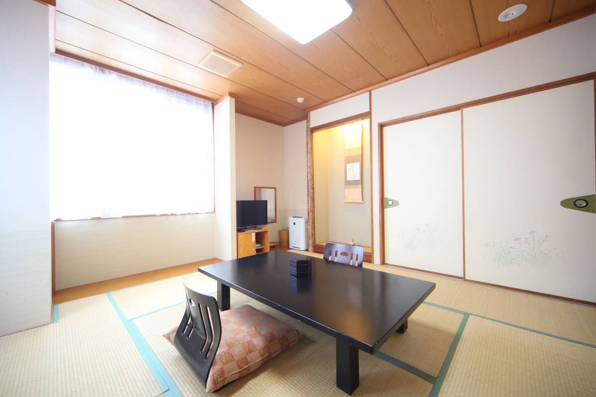 A traditional Japanese room with tatami flooring, a low table, and sliding doors.