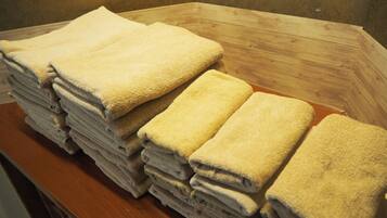 A stack of folded towels on a wooden surface in a room with a plain wall.