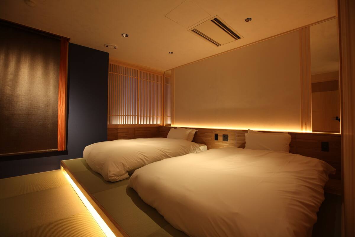 A hotel room with two beds, a large mirror, and a sliding shoji screen.