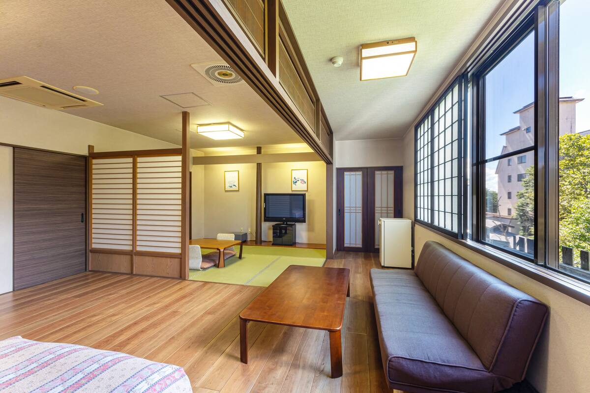 Une pièce de style japonais traditionnel, avec un sol recouvert de tatamis, une basse table en bois, un banc rembourré et un paravent coulissant de type shoji.