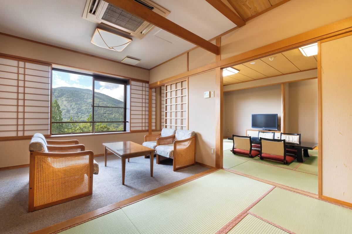 Une pièce de style japonais traditionnel, avec un sol recouvert de tatamis, un tapis de tatami au centre, une petite table basse et un canapé.