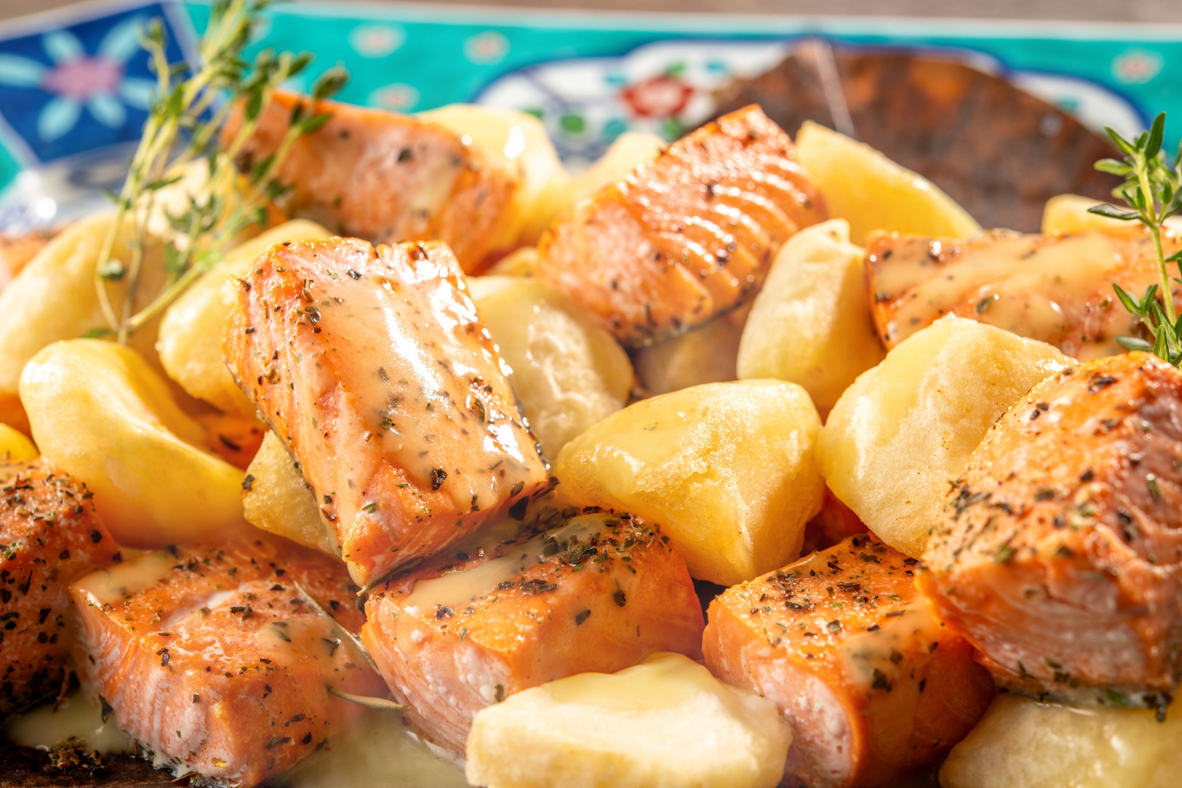 A plate of cooked salmon and potatoes garnished with herbs.