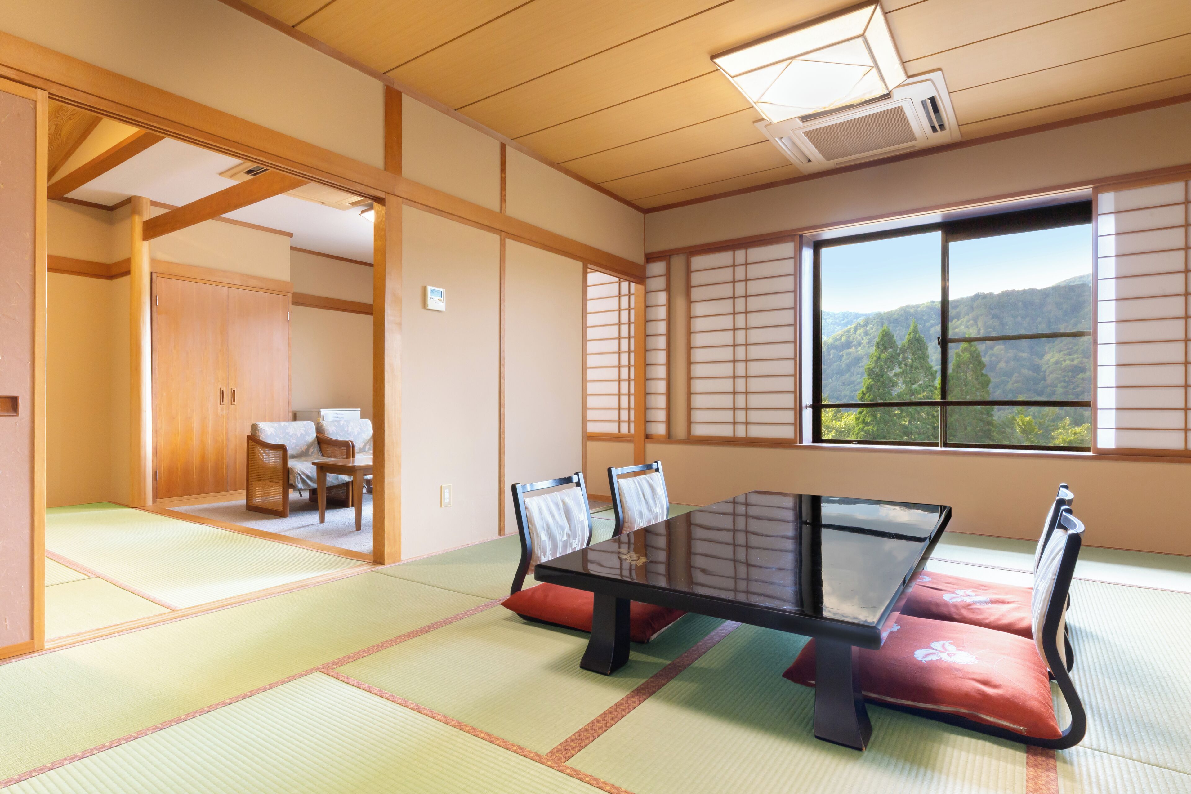 Una habitación japonesa tradicional con suelo de tatami, una mesa baja y puertas correderas.