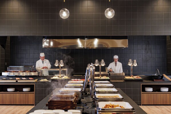 Un buffet avec plusieurs postes de service et des chefs qui préparent les plats.